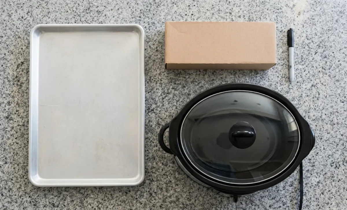 Basic batch cooking gear including a sheet pan, slow cooker, freezer bags, and marker